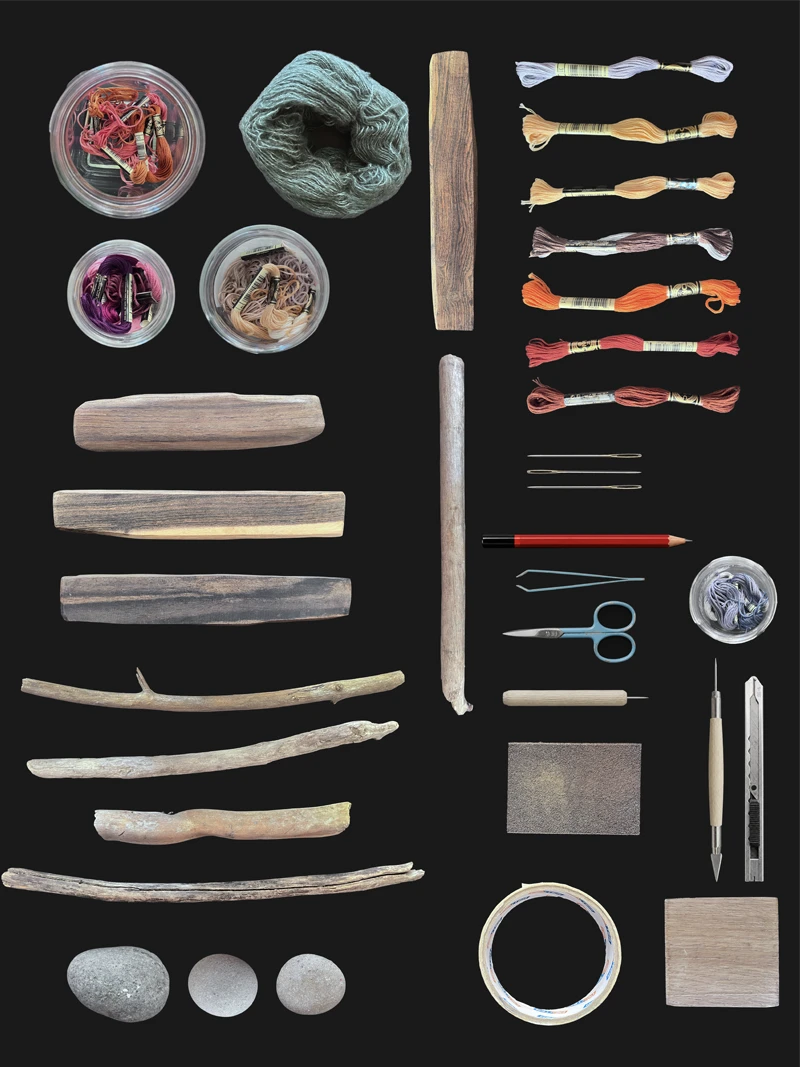 A flat-lay of the natural materials and hand tools used in Daniel Ortiz Studio's work — driftwood, stones, embroidery thread, needles and cutting tools